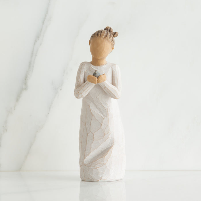 Ceramic angel figurine holding a heart on a white background