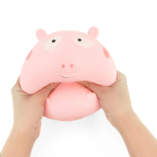 A pink Peppa Pig-shaped squishy stress toy being squeezed by two hands against a plain white background.