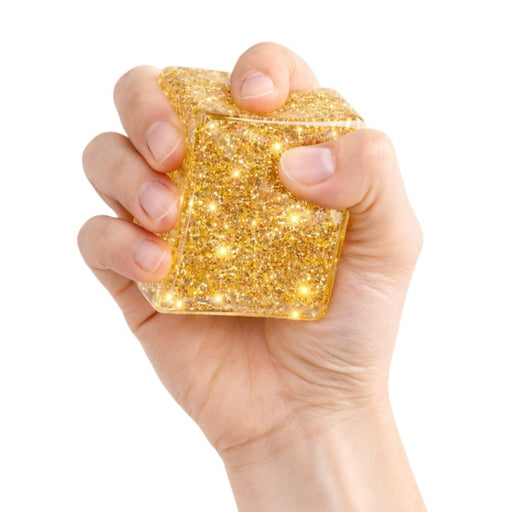 Hand holding a glittery gold square object against a white background