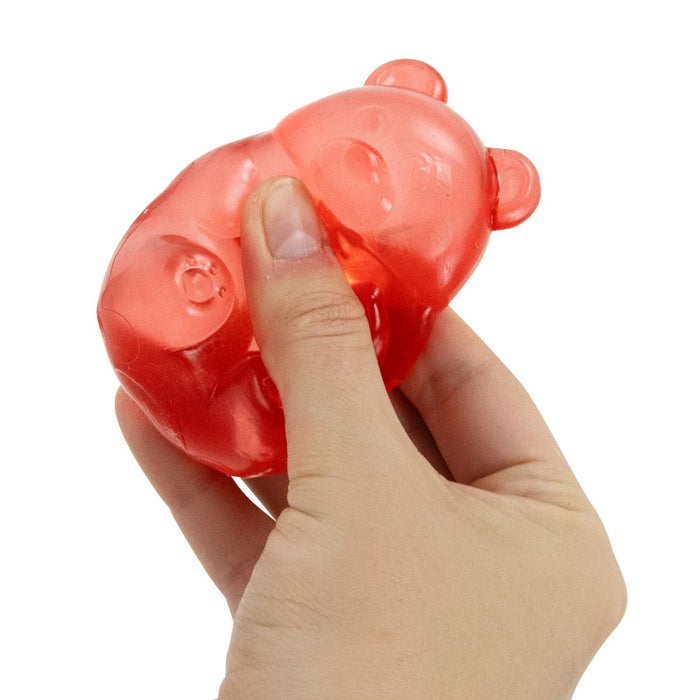 Hand squeezing a red gummy bear on a white background