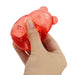 Hand squeezing a red gummy bear on a white background