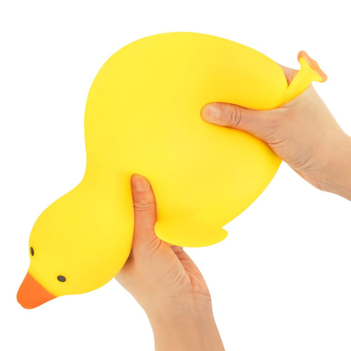 Yellow rubber duck being held by a hand on a white background
