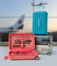 Stack of suitcases with a pink toolbox in front, airplane in the background