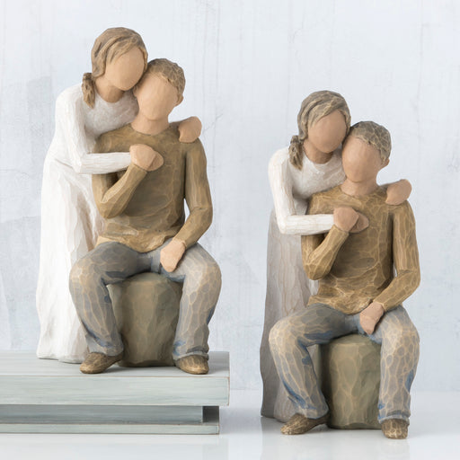 Two wooden figurines of a couple hugging each other on a white background