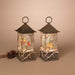 Two decorative lanterns with a winter scene inside on a beige background