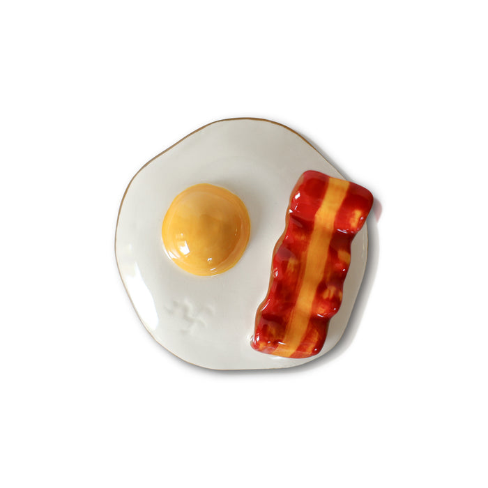 Decorative plate with a design of an egg and bacon on a white background