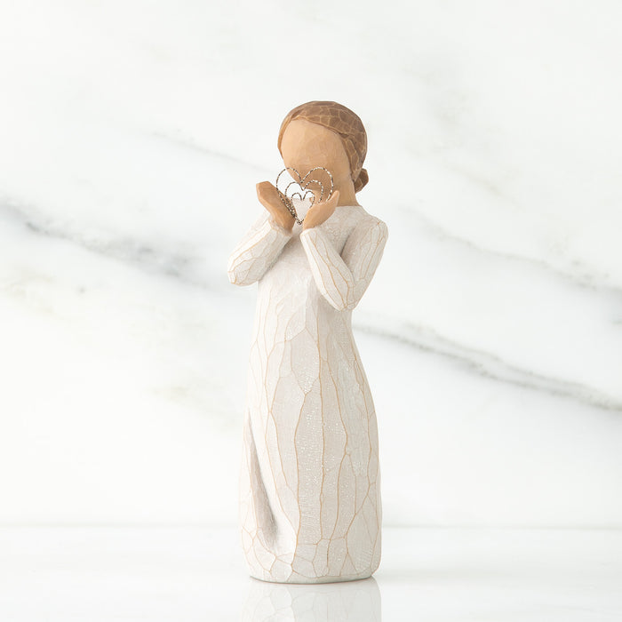 White ceramic figurine of a woman holding a heart-shaped object on a white background