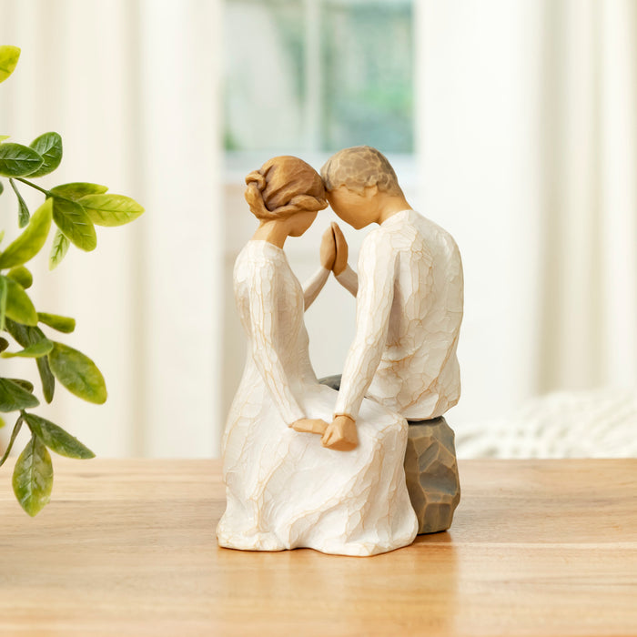 Statue of a couple embracing on a wooden surface with a blurred background