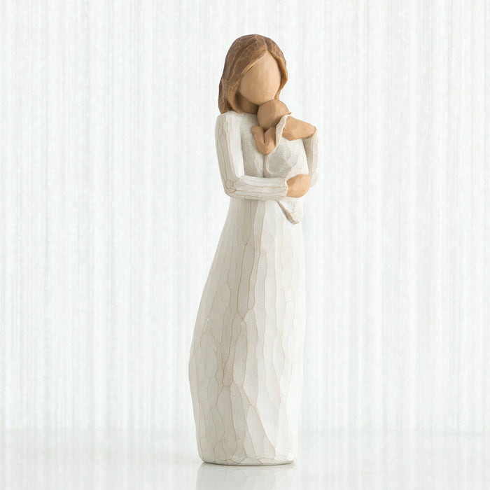 Statue of a woman in a long white dress holding a baby against a white background