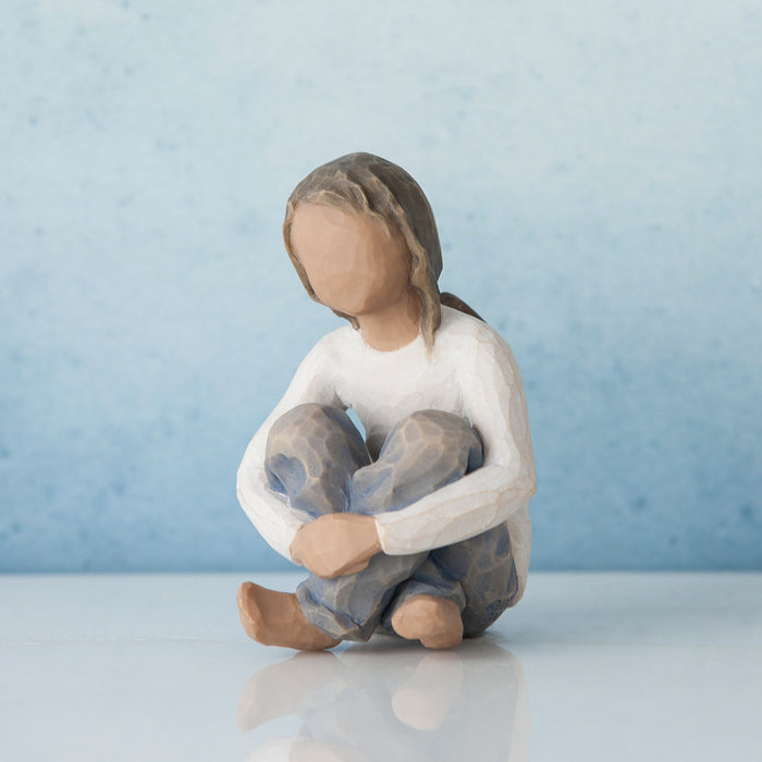 Ceramic figurine of a person sitting with a light blue background