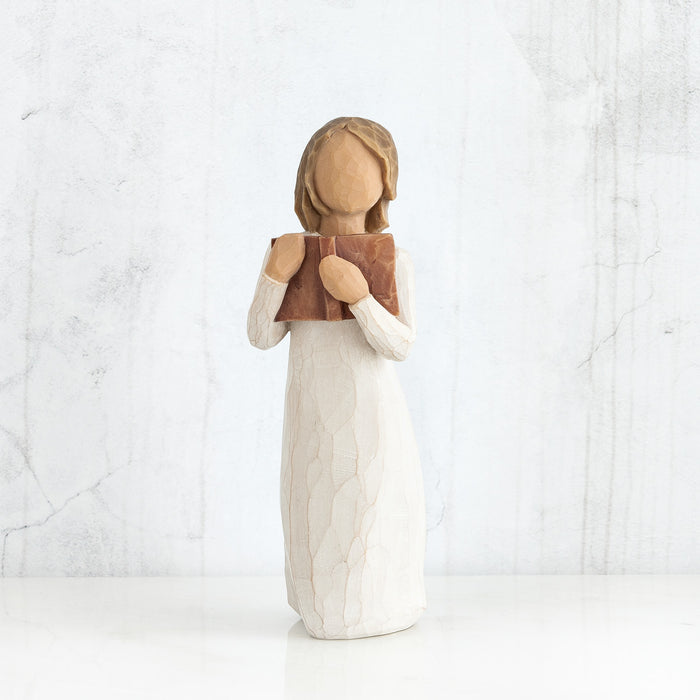 Wooden figurine of a woman holding a book against a white background