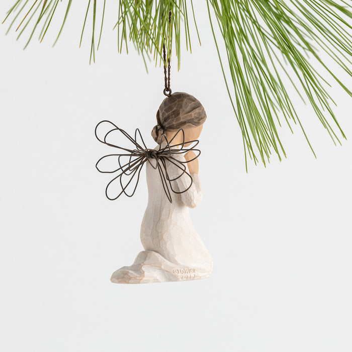 Wooden angel ornament with a butterfly wings hanging from a pine branch.
