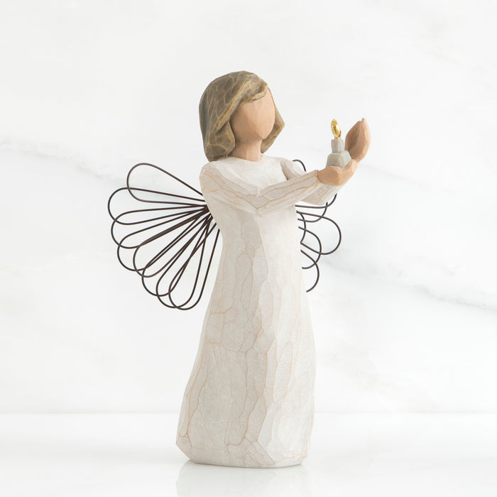 Standing angel in cream dress with wire wings, holding out candleholder with small gold-flamed candle in her hands