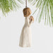 Decorative ornament of a woman holding a book, hanging from a branch on a light background