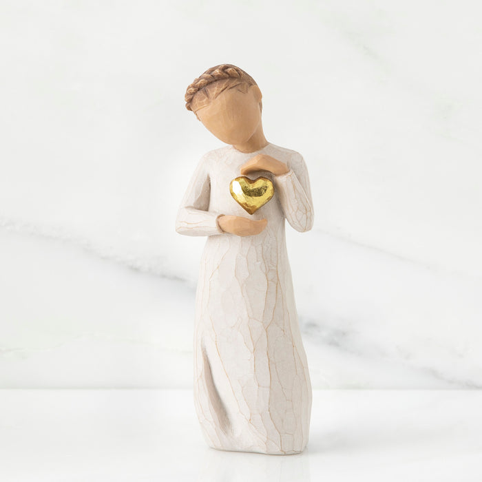 Figurine of a woman holding a gold heart against a white background