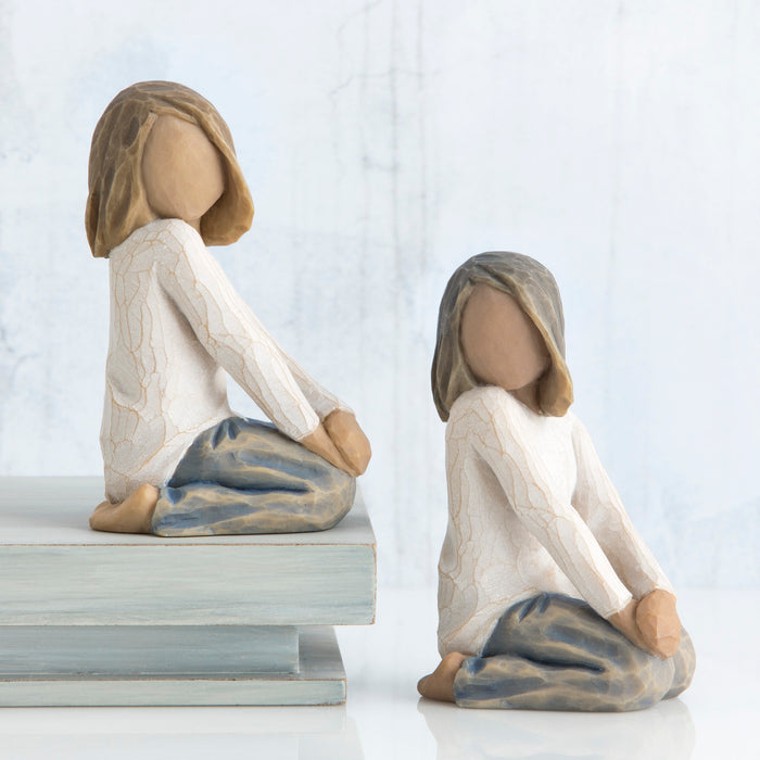 Two figurines of women sitting on a white background