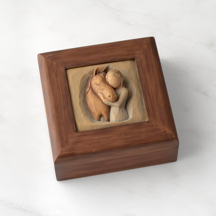 Reddish-brown square wood box with hinged lid: Carving of girl in green dress, with arms embracing reddish-color horse on lid of box
