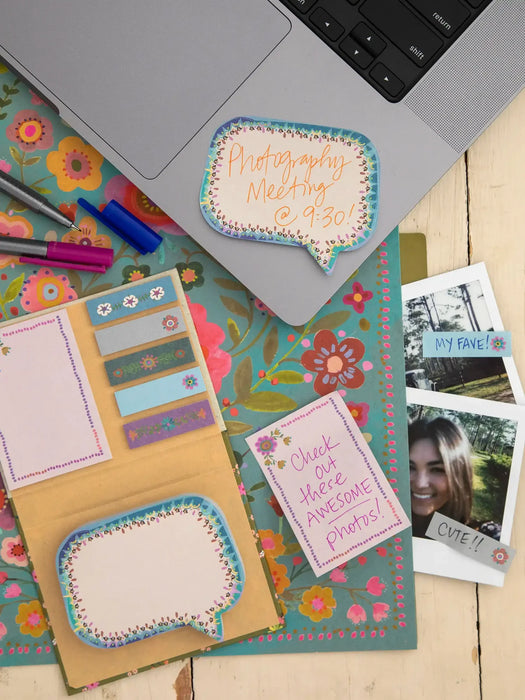 Notebook with decorative stickers and a laptop on a floral-patterned surface