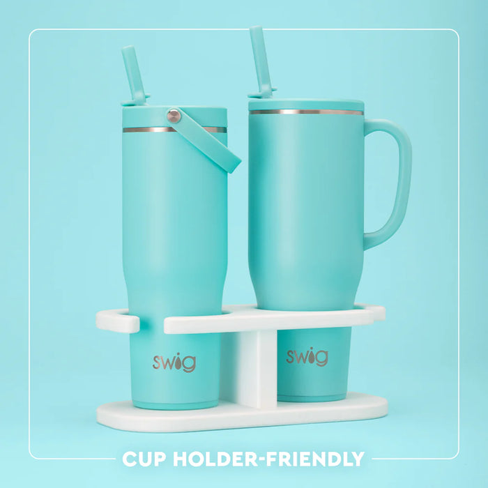 Two turquoise mugs with straws on a white stand against a light blue background