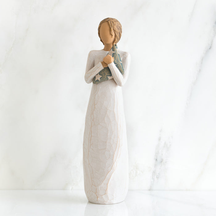 Decorative figurine of a woman holding a baby wrapped in a blanket on a white background