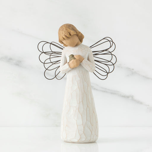 Angel figurine with wire wings on a marble surface