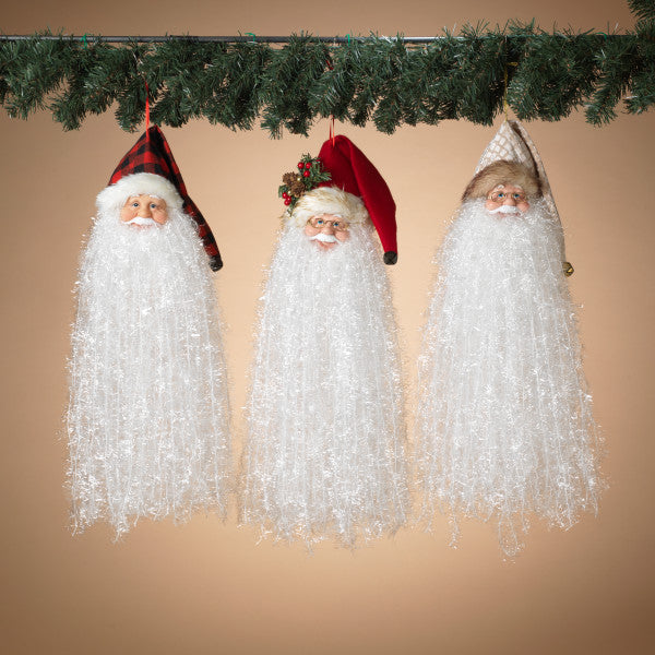 Three Santa Claus figurines hanging under a Christmas garland against a beige background