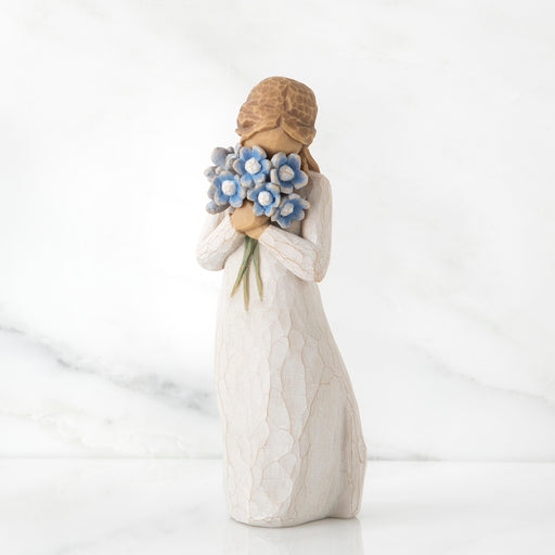 White figurine of a woman holding blue flowers on a white background