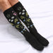 Black knee-high socks with floral pattern on a white background