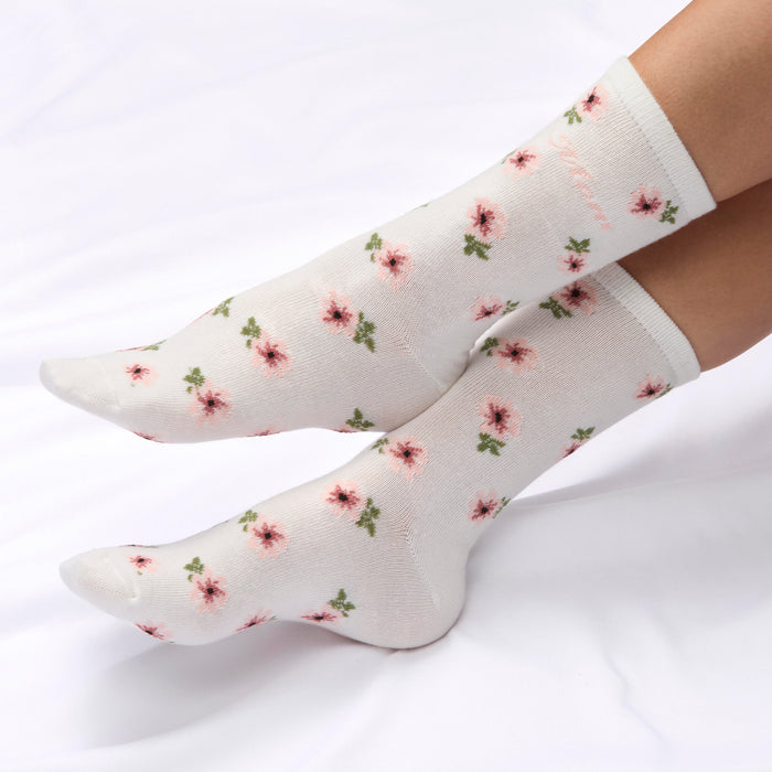 White knee-high socks with floral pattern worn by a person on a white background