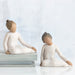 Two stone sculptures of women in a meditative pose on a white background