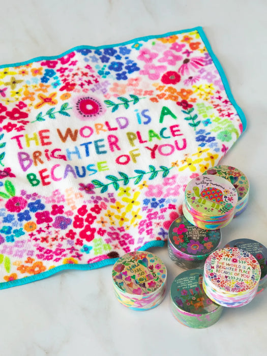 Colorful towel with motivational quote and small round containers on a white background