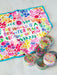 Colorful towel with motivational quote and small round containers on a white background