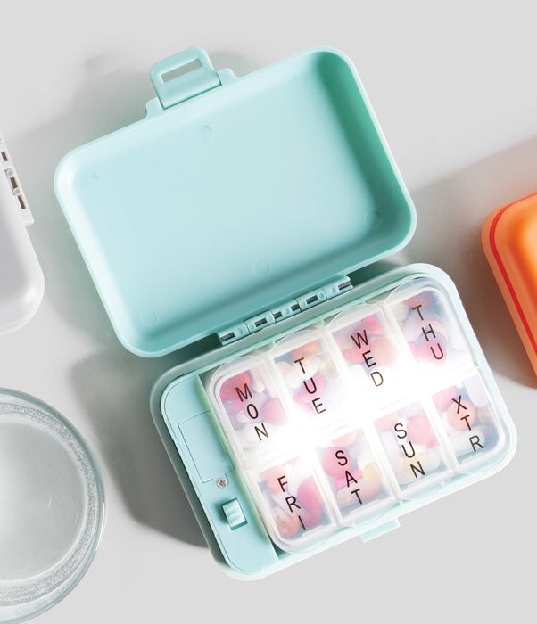 Weekly pill organizer with colorful days of the week labels on a light surface.