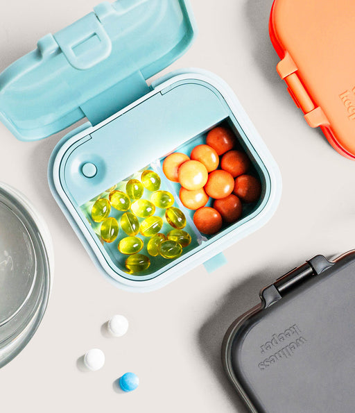 Small blue container with colorful capsules on a light gray background