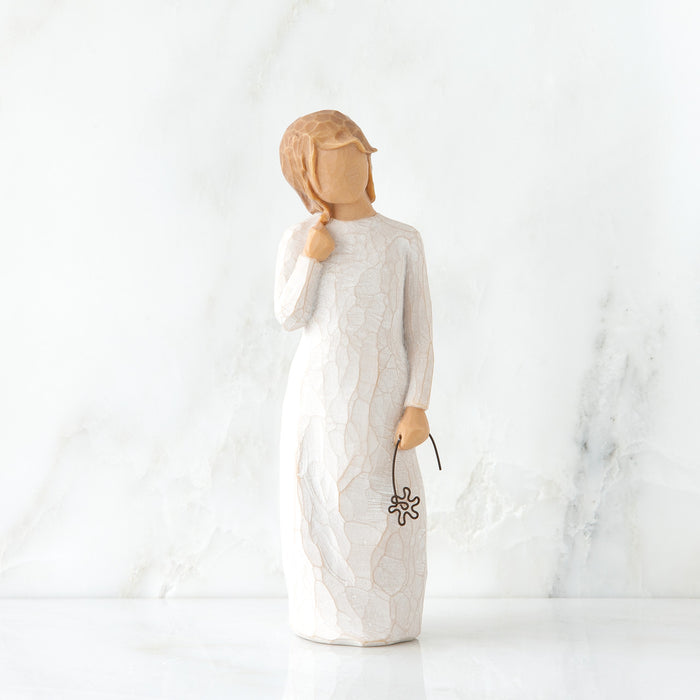 Figurine of a woman in a white dress holding a flower against a marble background