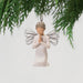 Angel ornament hanging from a branch with a plain background
