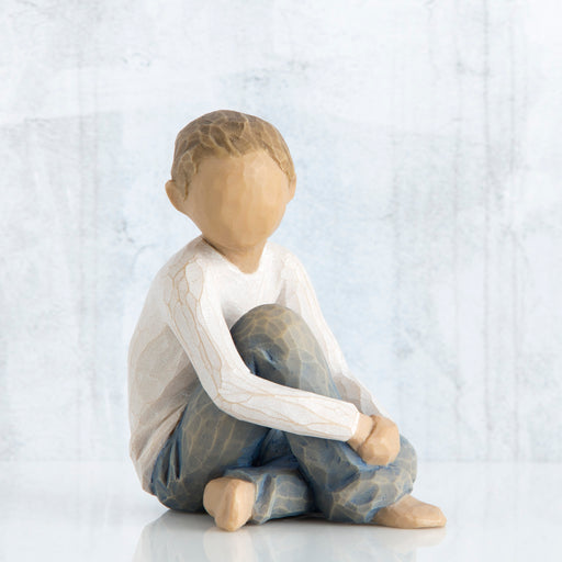 Wooden figurine of a child sitting on a white background