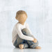 Wooden figurine of a child sitting on a white background
