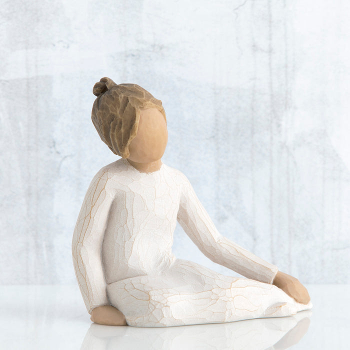 Wooden figurine of a woman sitting with a neutral background